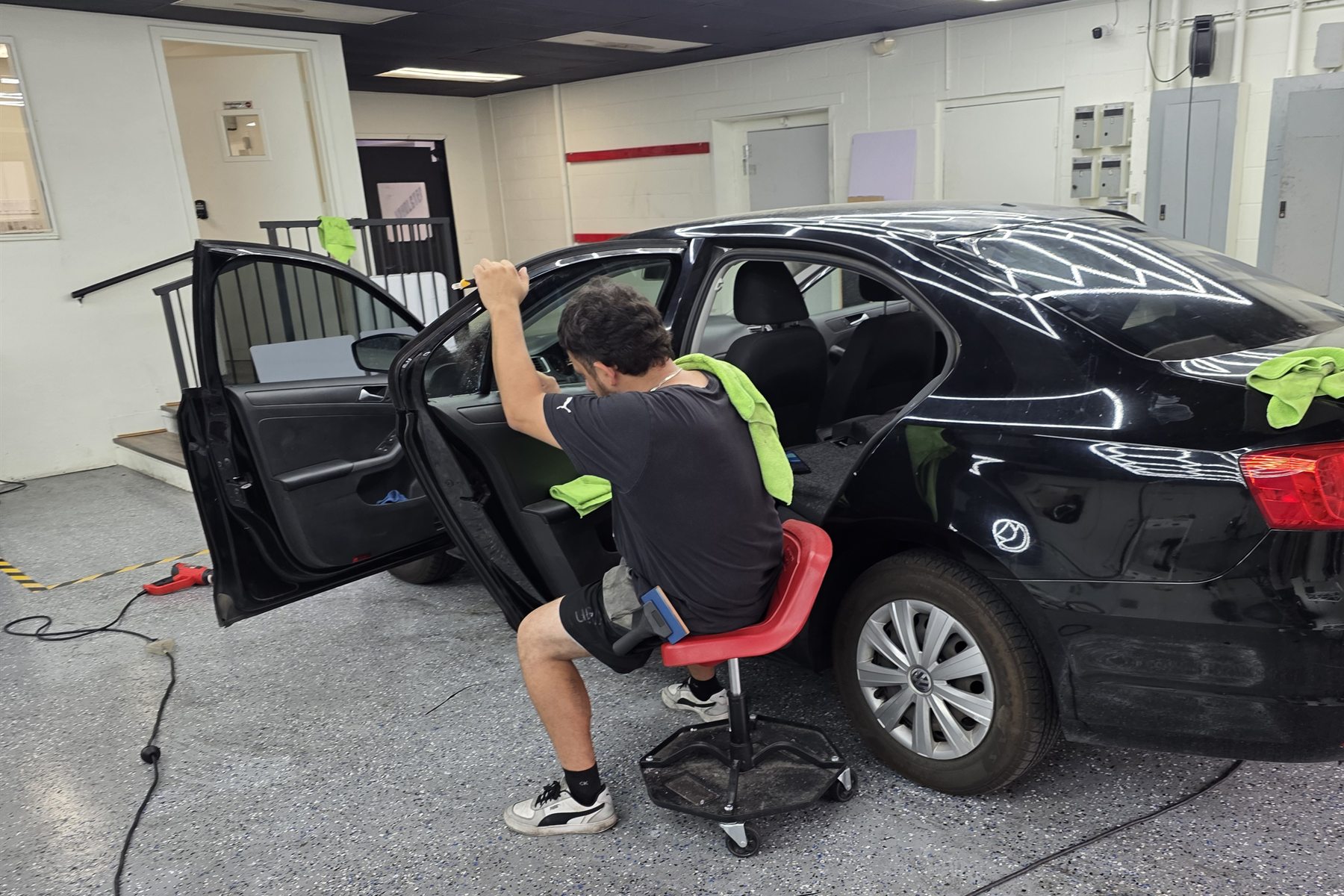 Tint Broz installer finishing film on a vehicle side window inside the shop
